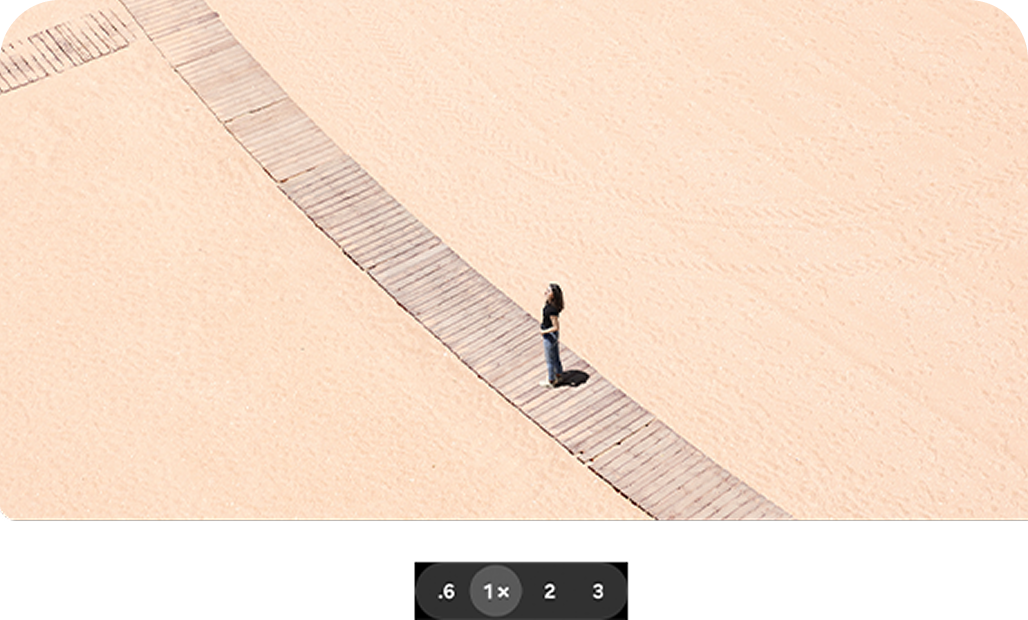 A woman standing on a beach walkway, with a standard 1x zoom.